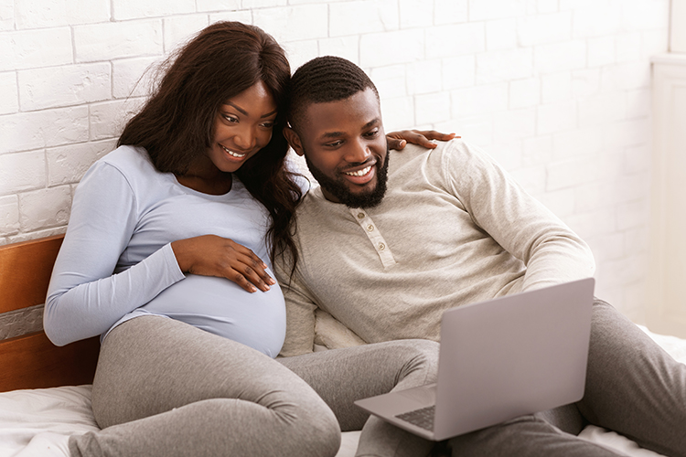 zwangere vrouw en man kijken op een laptop